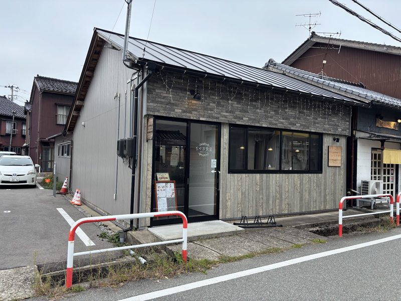 黒い屋根に板張りとタイル張りの外壁、角地に建つちぐさ食堂の外観